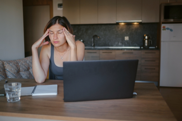 A woman trying to work on her laptop but struggling with the mental fatigue of brain fog