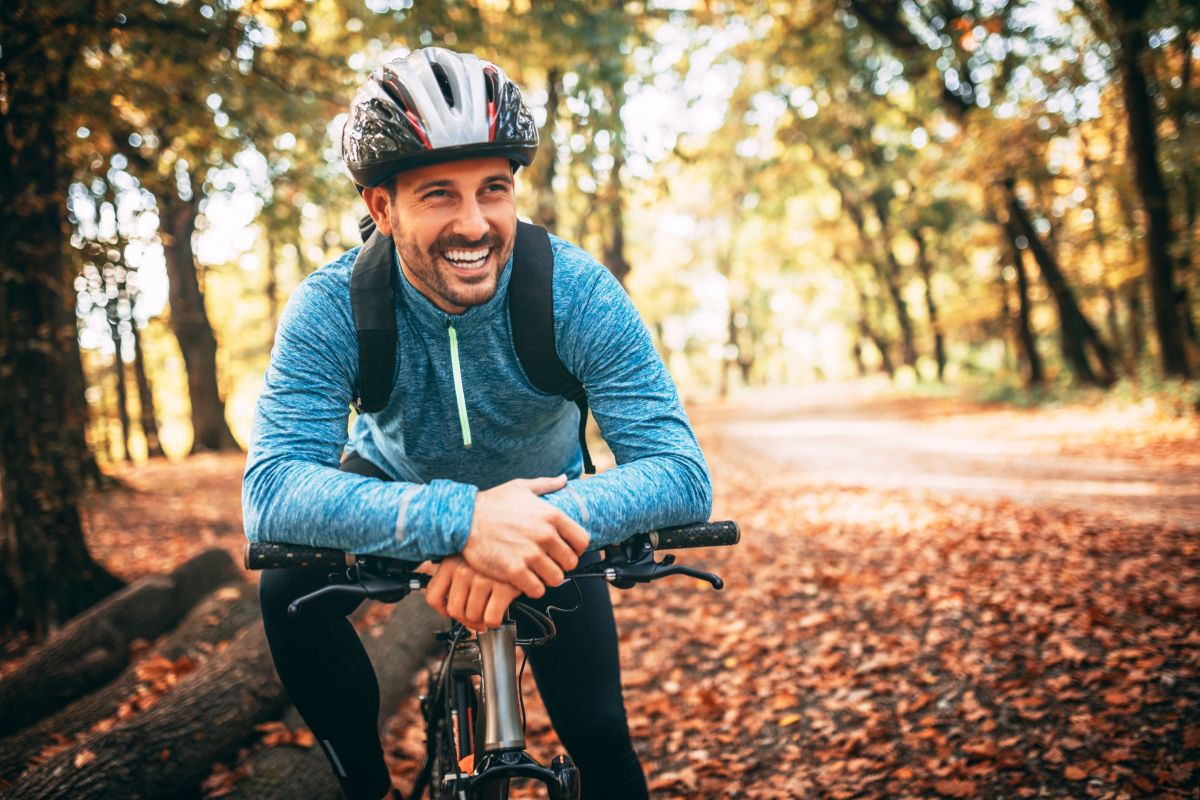 Happy man in blue cycling in autumn 