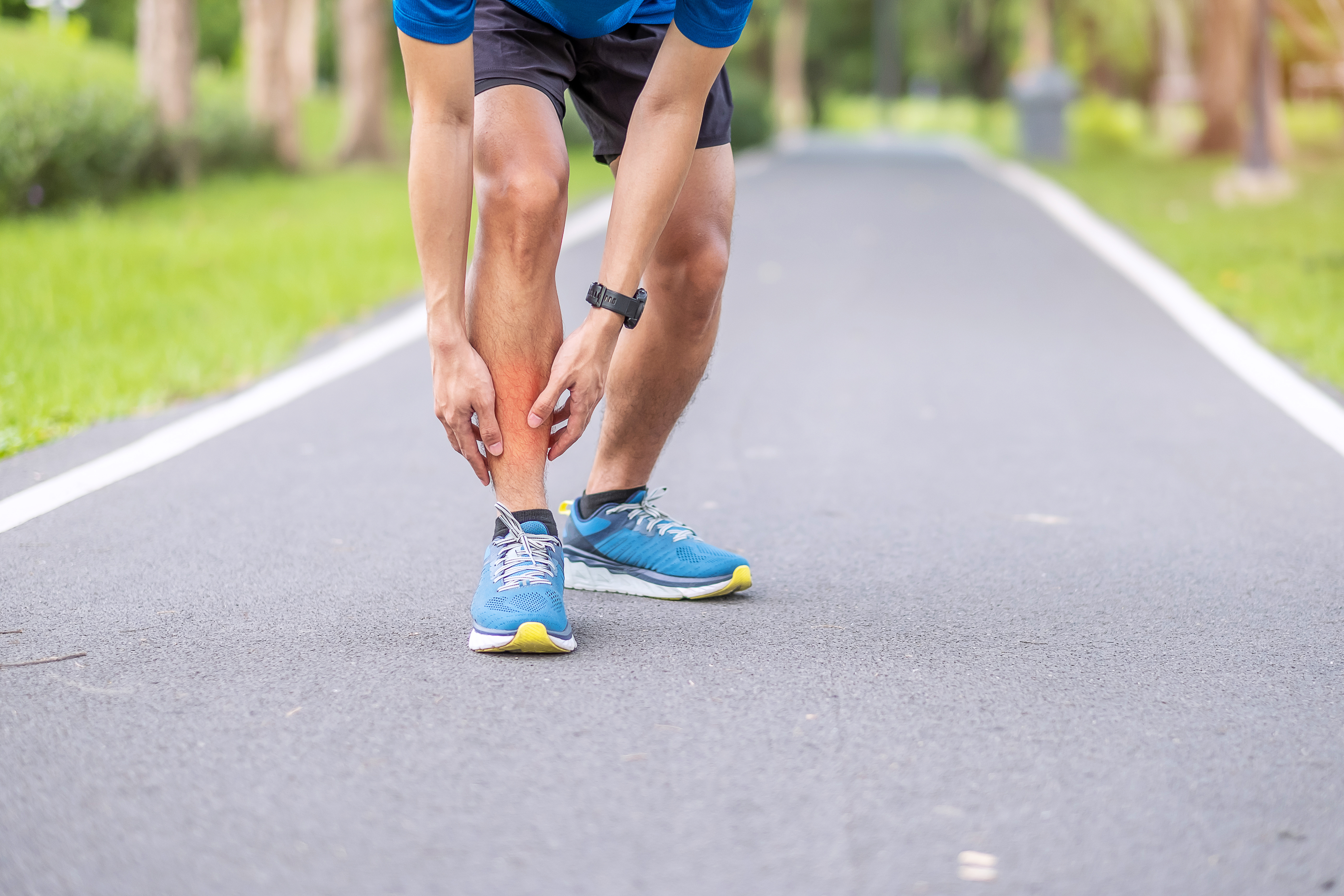 Man in running shoes holding shin